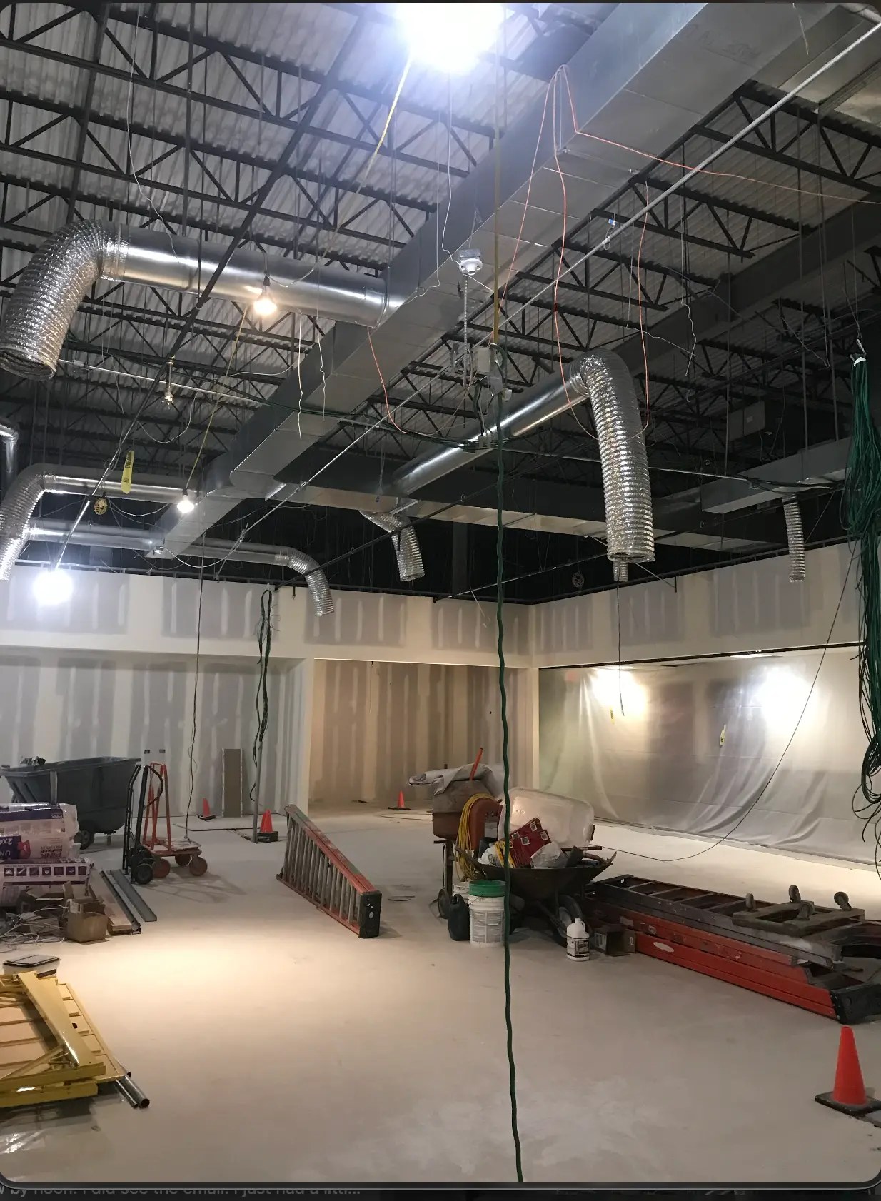 Open commercial space during build-out with exposed ceiling joists, suspended ductwork, and unfinished drywall partitions